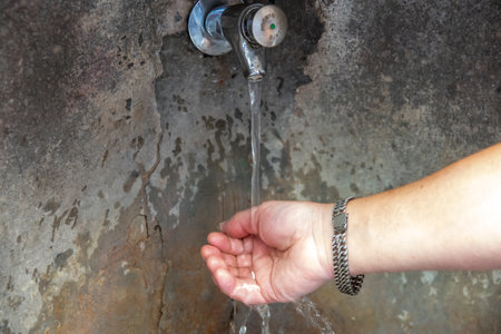 Man keep in the hands water splash. Stone water source in the old city.の写真素材