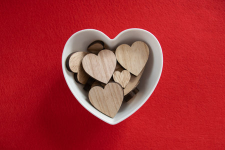 Much wood hearts in the plate on a red background with copyspace. Concept of Valentine's day and...