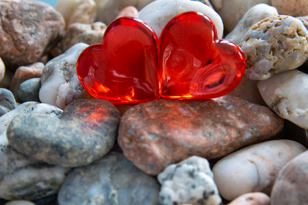 Two glass red bright heart on other stones near the river with sunny weather.の写真素材