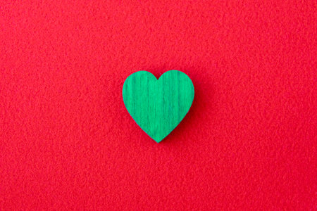 Green wood heart on the red fabric background. Romantic background for card.の写真素材