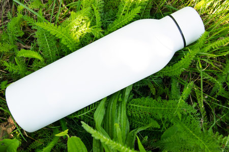 White thermo stainless bottle with refreshing water on the nature.の写真素材