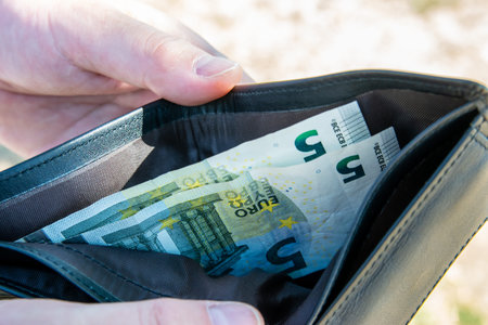 Man holding black leather wallet with euro money in the hands. Bills in the wallet for commerce...