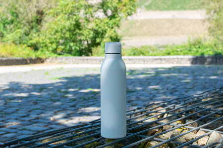 White stainless bottle with refreshing water stay in park on the nature.の写真素材
