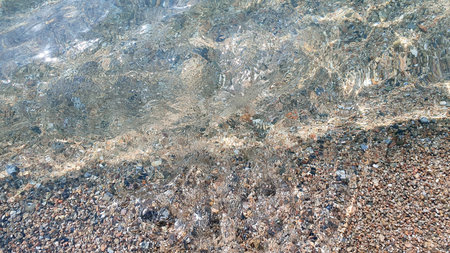 Sea stones. Clear transparent water and waves on sunny day with many stones.