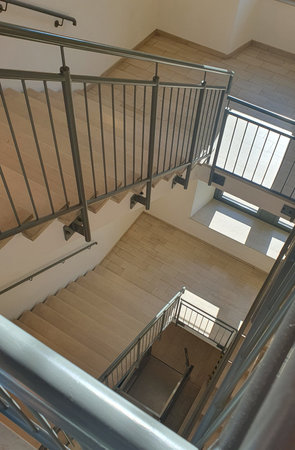 Internal staircase with marble stone beige stairs inside the building and metal railings. Close-up view of spiral.の写真素材