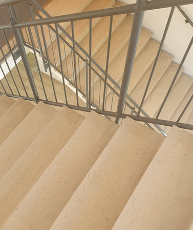 Internal staircase with marble stone beige stairs inside the building and metal railings.の写真素材