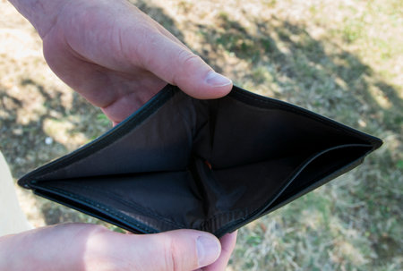 Man holding empty black leather wallet in the hands. The wallet without money for bankrupt concept.の写真素材
