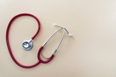 Red stethoscope on beige background with space for text. Medical instrument. Health care concept.の写真素材