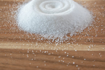 White granulated sugar for cooking food on the natural wood background.