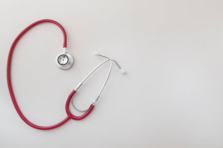 Red stethoscope on the white paper background. Medical instrument. Health care concept. Space for text.の写真素材