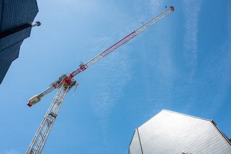 Metal building crane outside. Look above from backyard of an house blue sky and sun light in the city.の写真素材