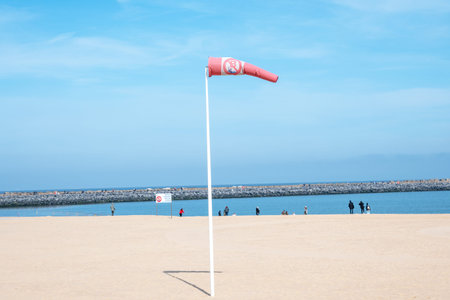 Windsock indicator of wind on the beach with yellow sand, blue sky, beautiful sea. Nature background...
