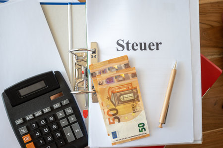 Blue and red folders with tax documents. Money euro bills, pen, calculator and paper on the table. Office steuer work for business.の写真素材