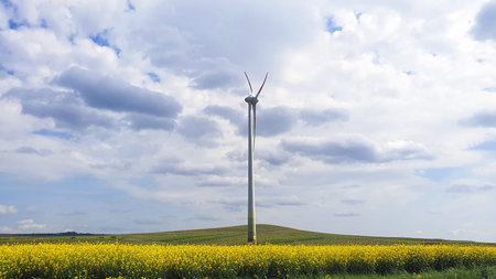 Big white windmillon the nature background with green field and blue sky. Wind turbine for...