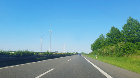 Cars drive on the highway and much white windmills on the nature background. Wind turbines for...