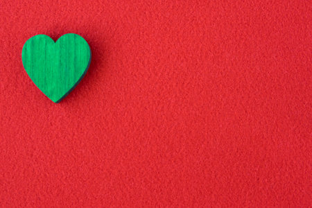 Green wood heart on the red fabric background with space for text. Greeting card concept.の写真素材