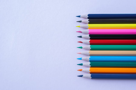 A lot of color pencils on the bright lila paper background. Close up. Design concept.