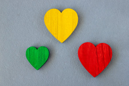Green, red, yellow wood hearts on the gray fabric background. Romantic greeting card.の写真素材