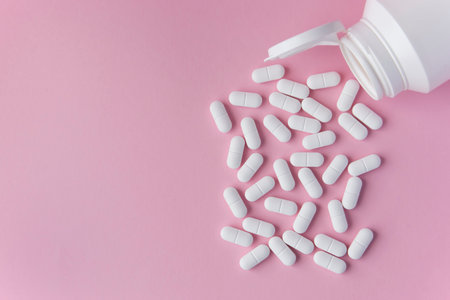 Medical pills and drugs in white bottle on the pink background. Healthcare concept. Space for text.の写真素材