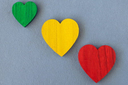 Wood red, yellow, green hearts on the gray fabric background. Romantic greeting card.の写真素材