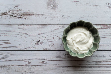 Natural white Greek yogurt in porcelain green bowl on the white wood table. Space for text.の写真素材