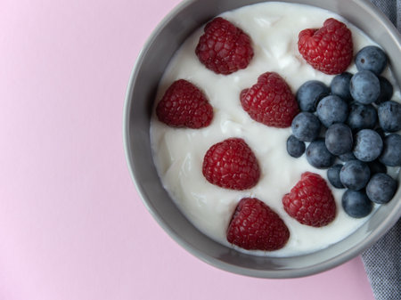 Natural fresh Greek yogurt with raspberry, blueberry berries in dark plate and napkin for healthy breakfast.の写真素材