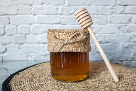 Honey jar with wood spoon stay on the table with rustic napkin.の写真素材