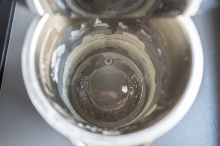 Black electric teapot with limescale surface. Hard water in metal kettle in the kitchen.の写真素材