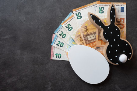 Black and white wood rabbit and egg with cash euro money for easter celebration on the black stone...