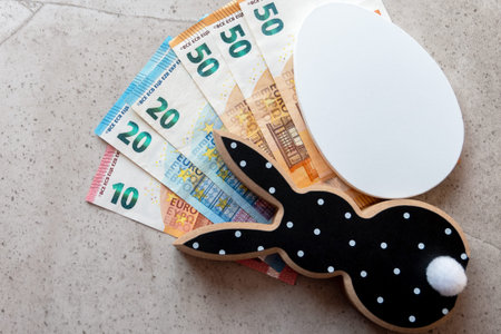 Black and white wood rabbit and egg with cash euro money for easter celebration on the stone...