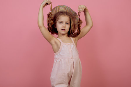 Little girl with pigtails wearing hat on pink backgroundの写真素材