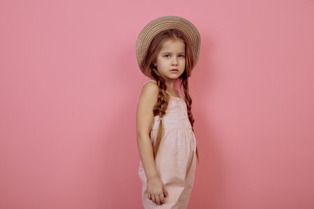 Little girl with pigtails wearing hat on pink backgroundの写真素材