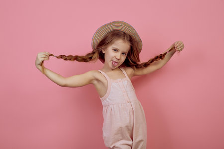 Little girl with pigtails wearing hat on pink backgroundの写真素材