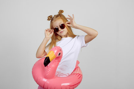 Redhead teen girl with flamingo pool float toy wearing glasses. Summer, vacationの写真素材
