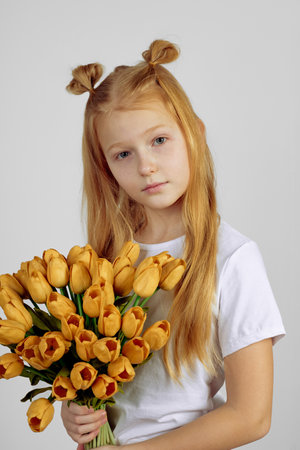 Teen redhead girl with yellow tulips, flowers. International women's day.の写真素材