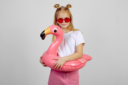 Redhead teen girl with flamingo pool float toy wearing glasses. Summer, vacationの写真素材