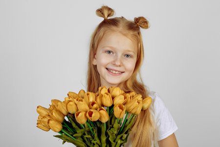 Teen redhead girl with yellow tulips, flowers. International women's day.の写真素材