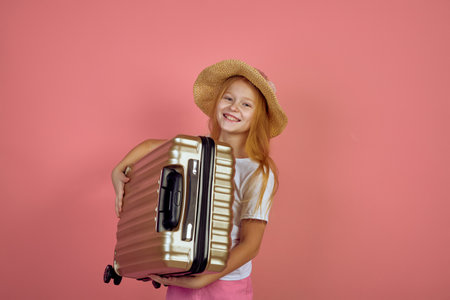 Redhead smiling teen girl holding suitcase wearing hat. Luggage, travelling, vacation.の写真素材