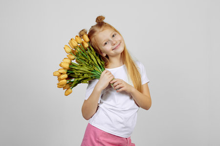 Teen redhead girl with yellow tulips, flowers. International women's day.の写真素材