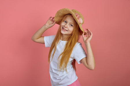 Teen redhead smiling girl on pink background with hat.の写真素材