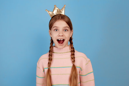 Little surprised girl with golden crown on blue background.の写真素材