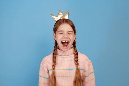 Little surprised girl with golden crown on blue background.の写真素材