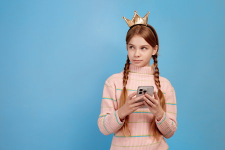 Little girl with crown chatting with her phone.の写真素材