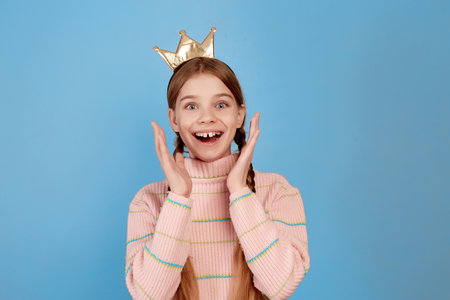 Little surprised girl with golden crown on blue background.の写真素材