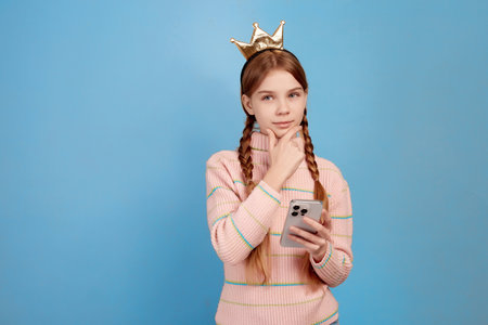 Little girl with crown chatting with her phone.の写真素材