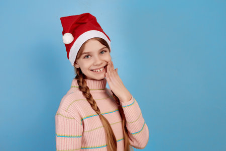 Little smiling girl wearing Santa hat on blue background.の写真素材