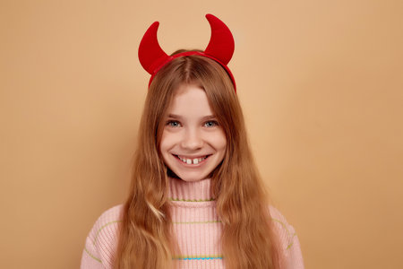 Little girl with red devil horns happy and smiling expression.の写真素材