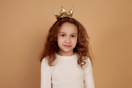 Little African-American girl with long curly hair on beige background.の写真素材