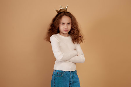 Little offended African-American girl with long curly hair on beige background.の写真素材