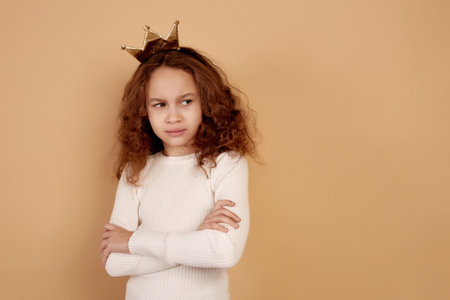 Little offended African-American girl with long curly hair on beige background.の写真素材